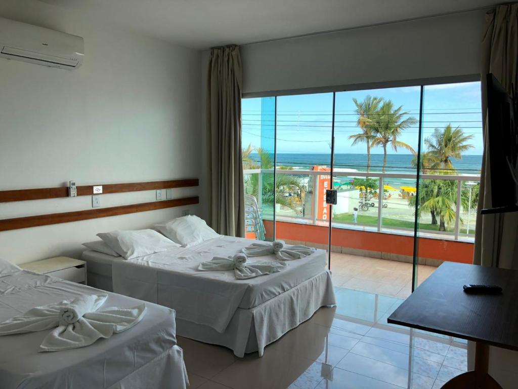 a hotel room with two beds and a view of the ocean at HOTEL ENSEADA BEIRA MAR in Guarujá