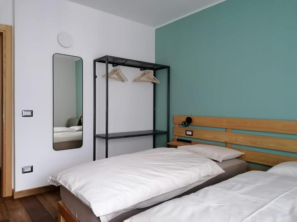 two twin beds in a room with a mirror at ALPINO B&B in Chiesa in Valmalenco