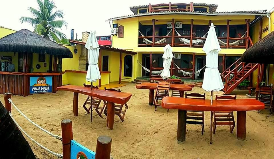 a restaurant with tables and umbrellas in front of a building at Morro Beach Hotel in Morro de São Paulo