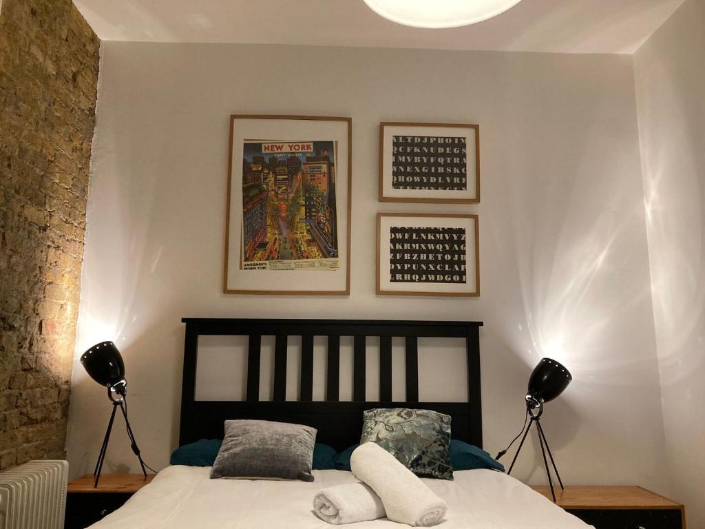 a bedroom with a bed with two lamps and pictures on the wall at Goswell Central Apartment by DC London Rooms in London