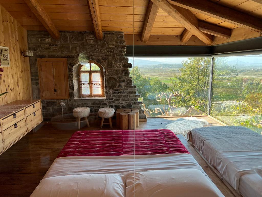 a bedroom with a large bed and a large window at Mrizi i Zanave Agroturizëm in Lezhë