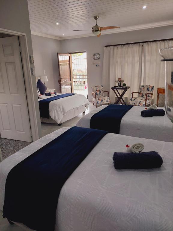 a bedroom with three beds with blue and white sheets at AKKERHUIS GASTEHUIS in Bloemfontein