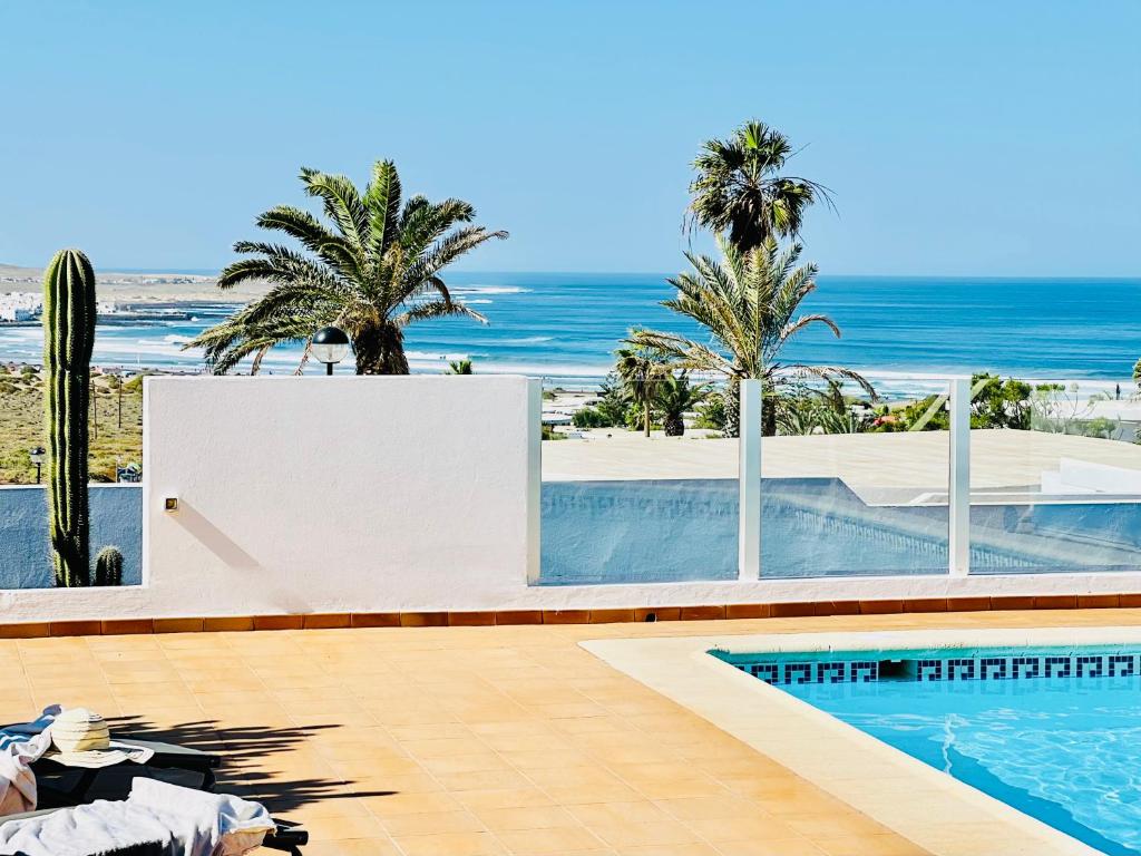 a swimming pool with palm trees and the ocean at Canaryislandshost I Marquesa in Famara