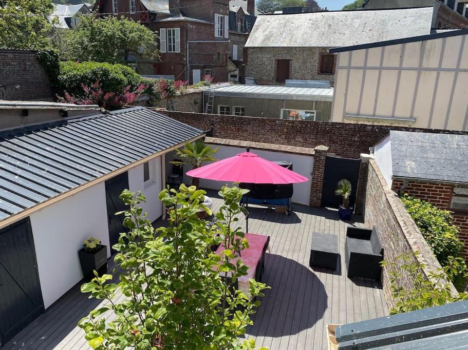 a patio with a pink umbrella and a table and chairs at Bel appartement avec jardin au coeur d'Etretat in Étretat