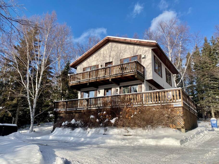 a house with a deck in the snow at Chalet «L&#39;Autrichien» de Charlevoix in Petite-Rivière-Saint-François