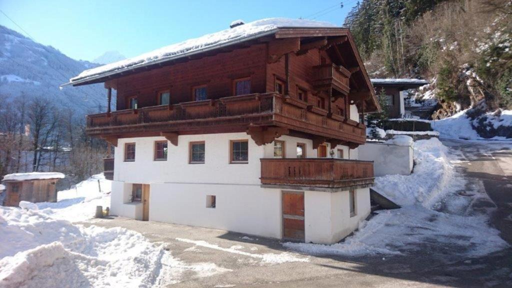 a building with a wooden roof in the snow at Ferienchalet Kreuzlauhof MAY-101 in Schwendau