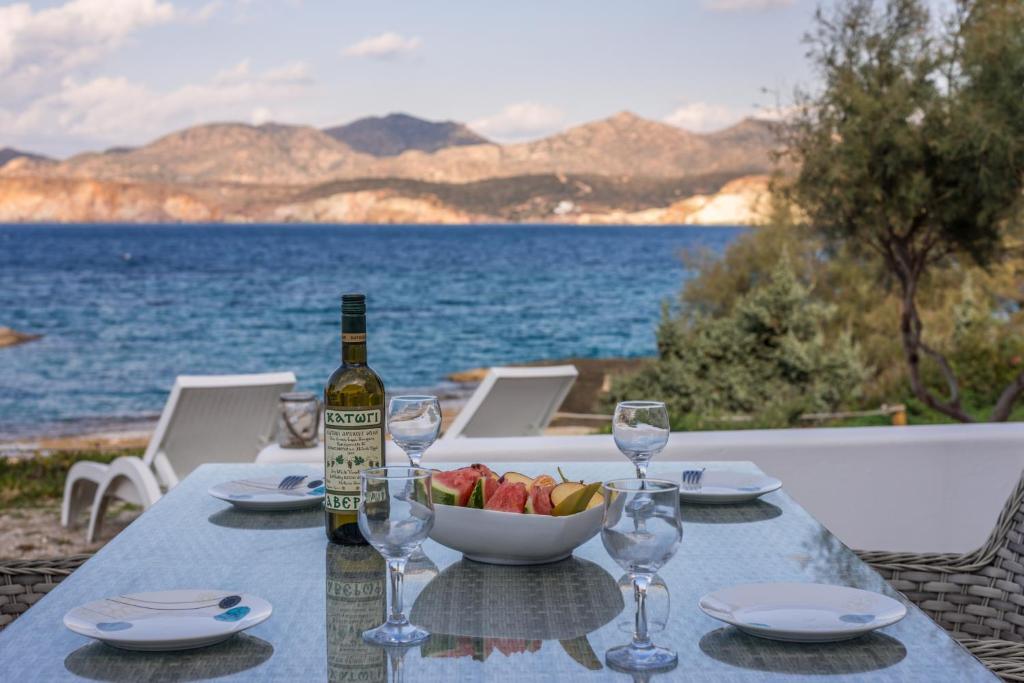 a table with a bottle of wine and a bowl of fruit at Venia's Guesthouse in Pollonia