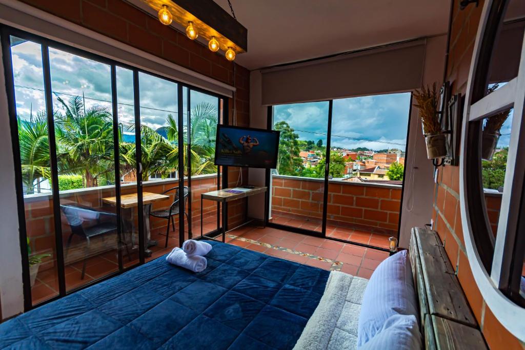 a room with a bed and a tv and windows at Hotel Le Chateau Guatape in Guatapé