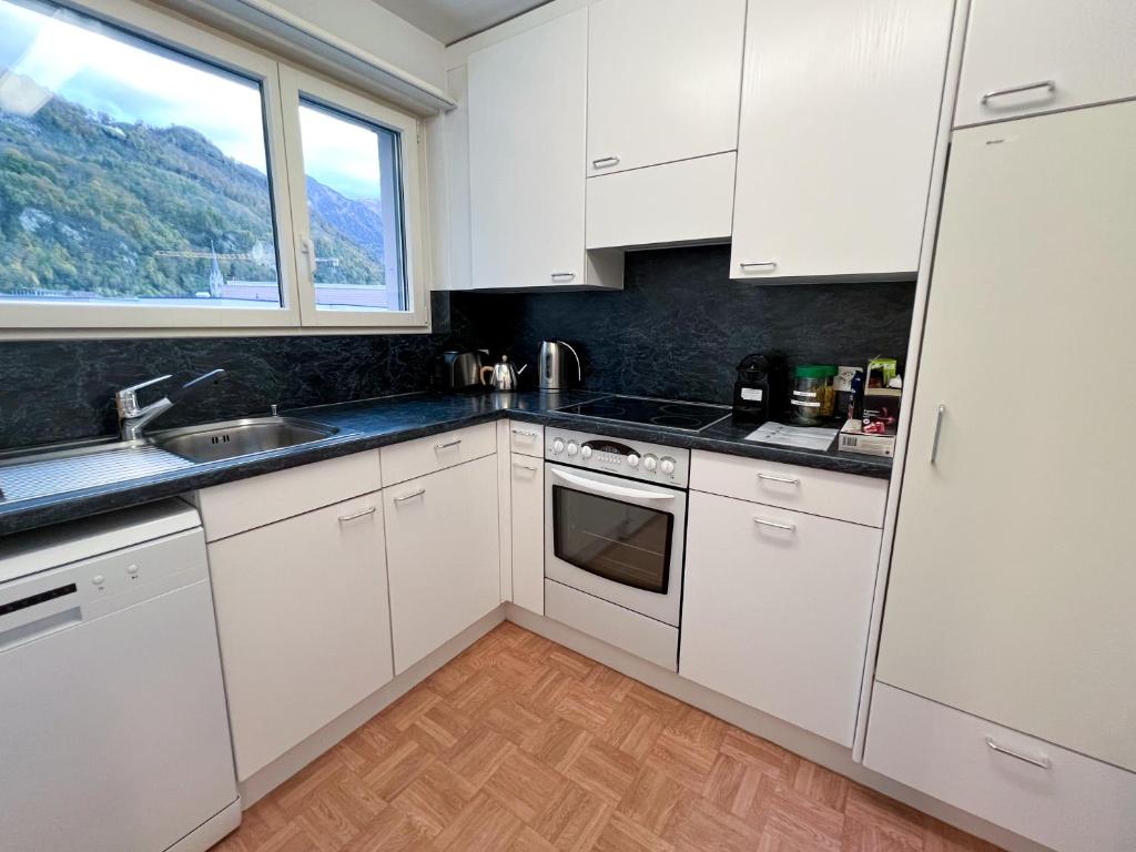 cocina con armarios blancos, fregadero y ventana en Schöne grosse Attika-Wohnung im Zentrum von Vaduz inkl. Parkplatz, en Vaduz