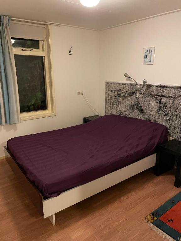 1 dormitorio con cama morada y ventana en Boerenkiel Vakantiehuisjes, en De Kiel