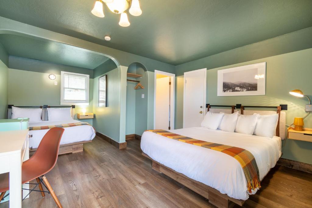 Habitación con 2 camas, paredes verdes y suelo de madera. en Dew Duck Inn, 