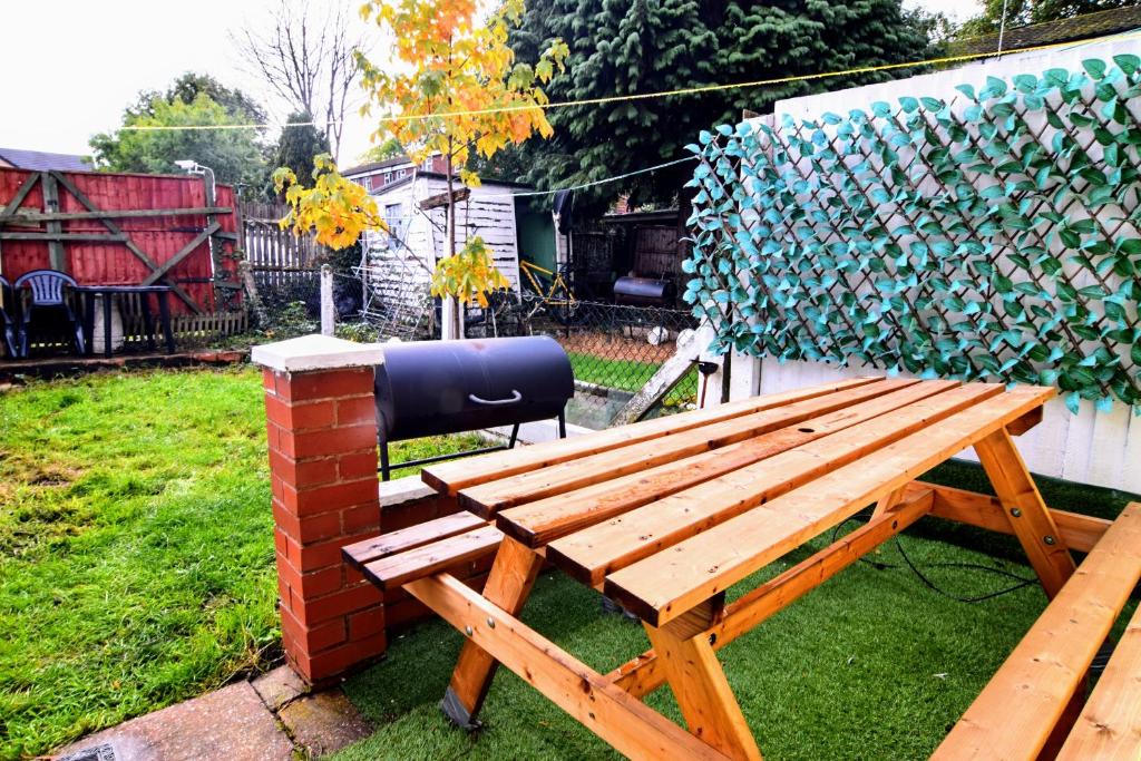 eine Holzbank neben einer Backsteinmauer in der Unterkunft The Chinatown Home - Private Garden, NETFLIX, BBQ & Bar in Birmingham