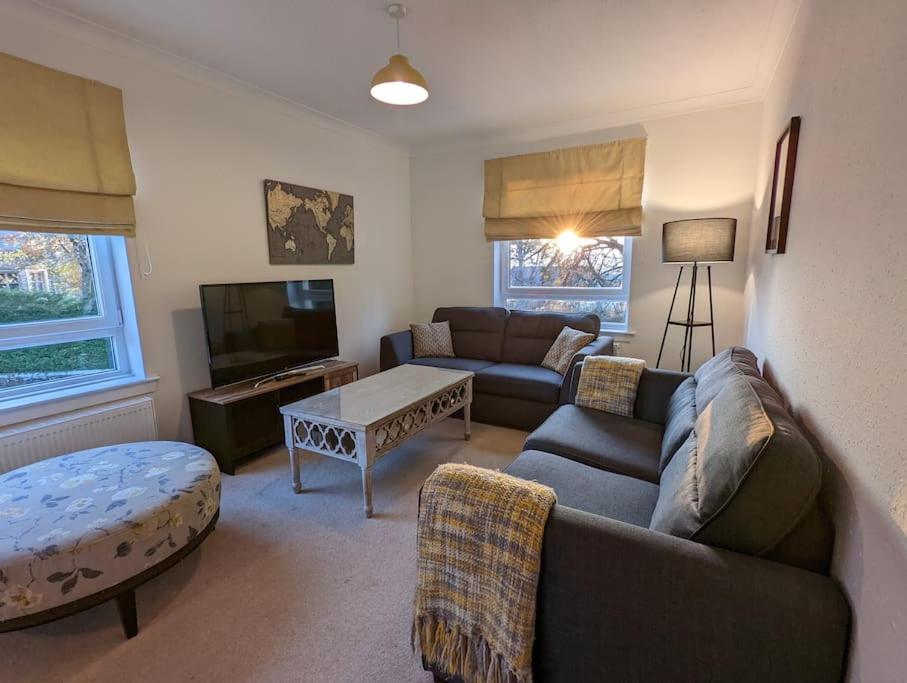 een woonkamer met een bank en een tafel bij Two bed flat in a quiet village near Stirling in Bridge of Allan