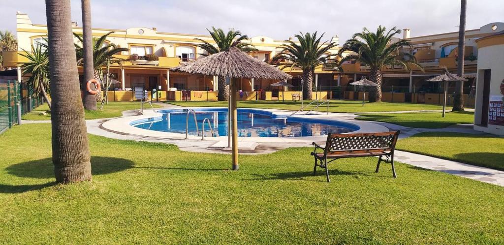 un banco y una sombrilla junto a la piscina en Apartamento Urb La Tortuga I, en Tarifa