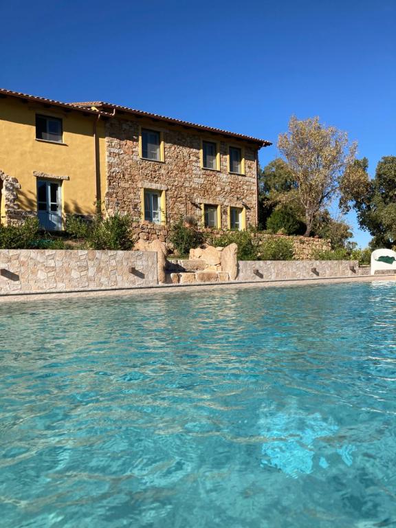 a stone house with blue water in front of it at Agriturismo Is Conchisceddas in Gonnosfanàdiga