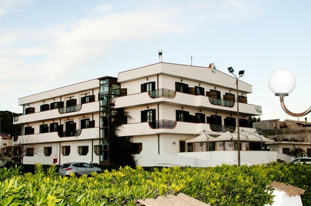 un edificio bianco con un'auto parcheggiata di fronte di Hotel Onda Bleu a Botricello