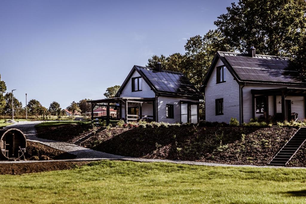 a white house and a house with a yard at Domki na Kaszubach - Chabry i Rumianki - Roztoka, Przywidz - Basen Sauna Jacuzzi KASZUBY in Roztoka