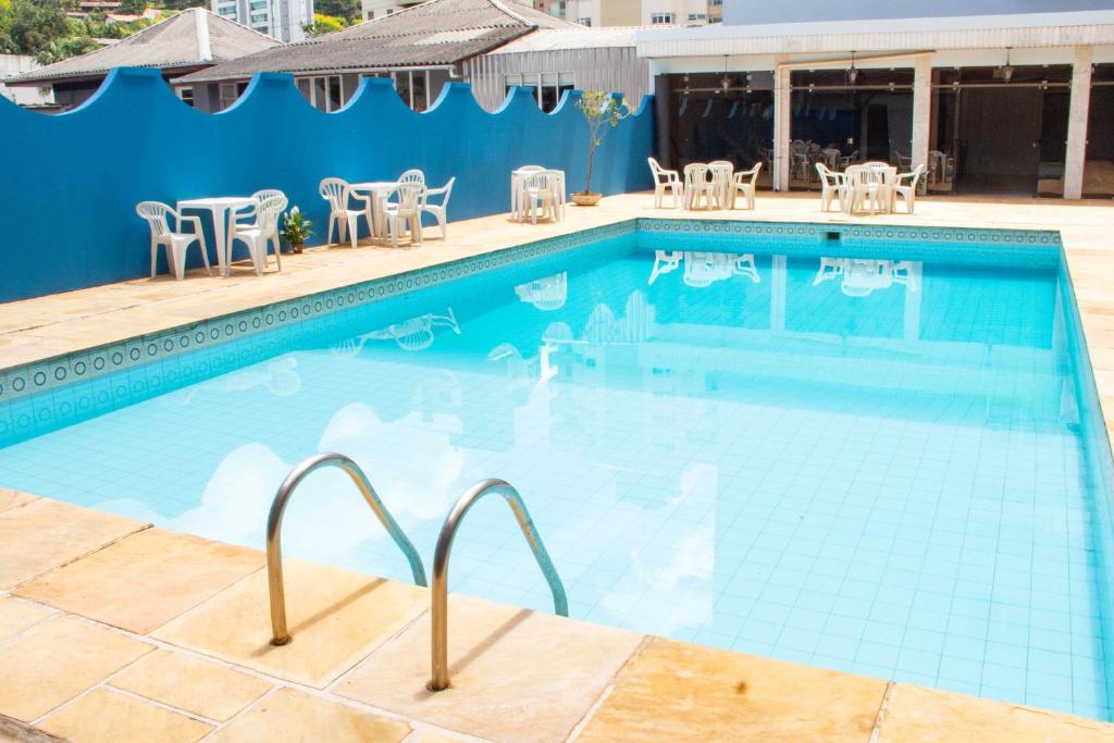 a swimming pool with tables and chairs next to a building at HOTEL DOMHOF in Blumenau