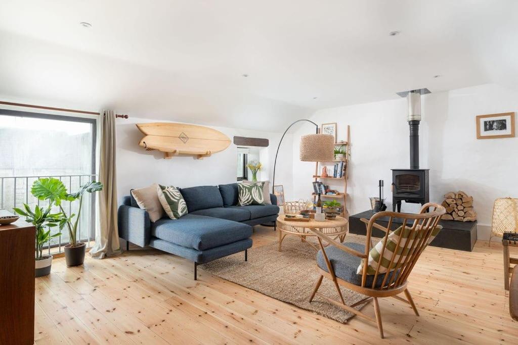 uma sala de estar com um sofá azul e uma mesa em Cosy cottage, walk to Porthcurno beach, Pedn Vouder, Minack & PK Museum em Penzance