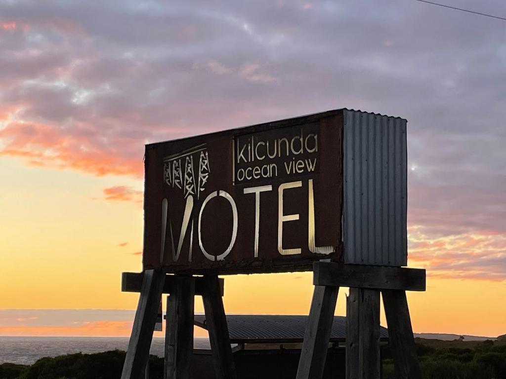 een bord voor een motel met de zonsondergang op de achtergrond bij Kilcunda Ocean View Motel in Kilcunda
