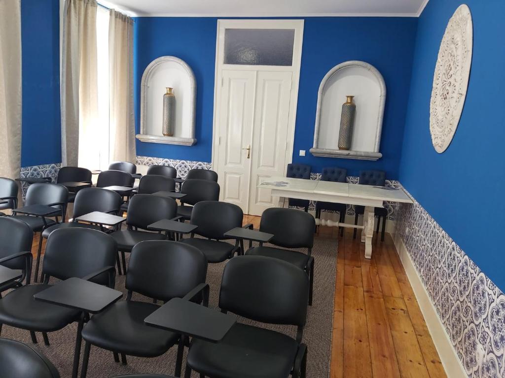 a room with blue walls and black chairs at Nerinha Residence in Coruche