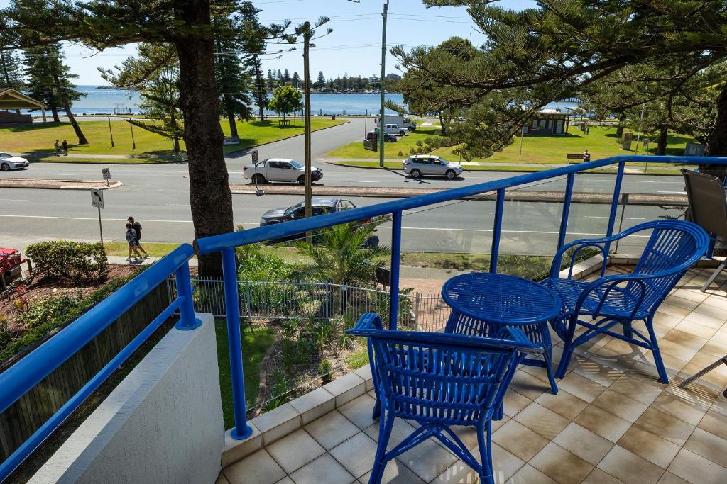 two blue chairs on a balcony with a view of a street at Heritage 201 in Tuncurry