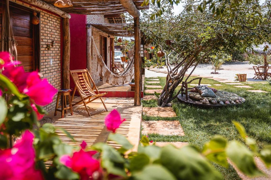 eine Veranda eines Hauses mit einer Feuerstelle und rosa Blumen in der Unterkunft Vila Castanheiras in Barra Grande