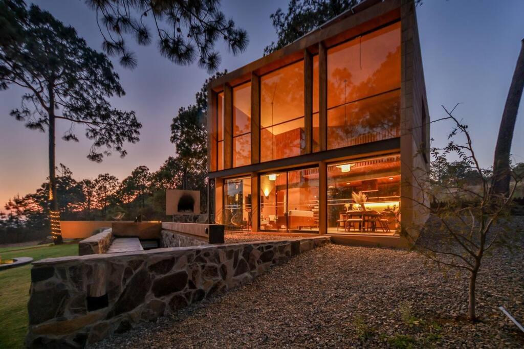 uma casa com grandes janelas e uma parede de pedra em Cabaña de lujo muy cómoda, Internet alta velocidad, Fogatero y jardín c/Tina em Mazamitla