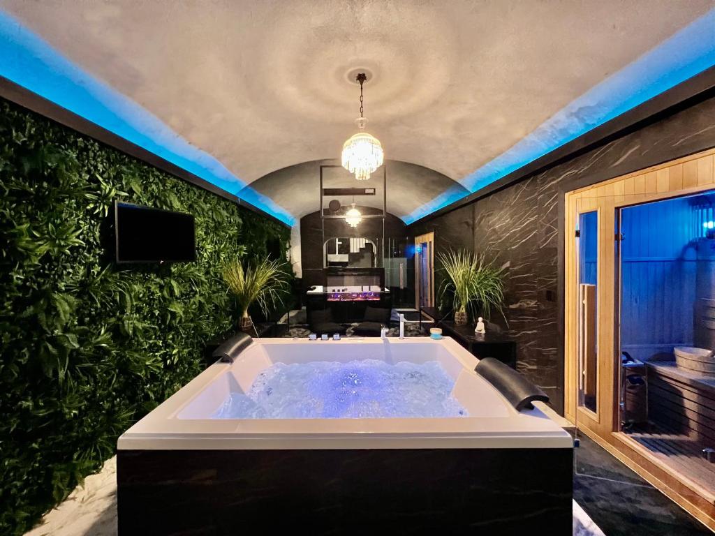 Romantic Wellness Apartment COLOSSEO في روما: حوض استحمام كبير في غرفة بها نباتات