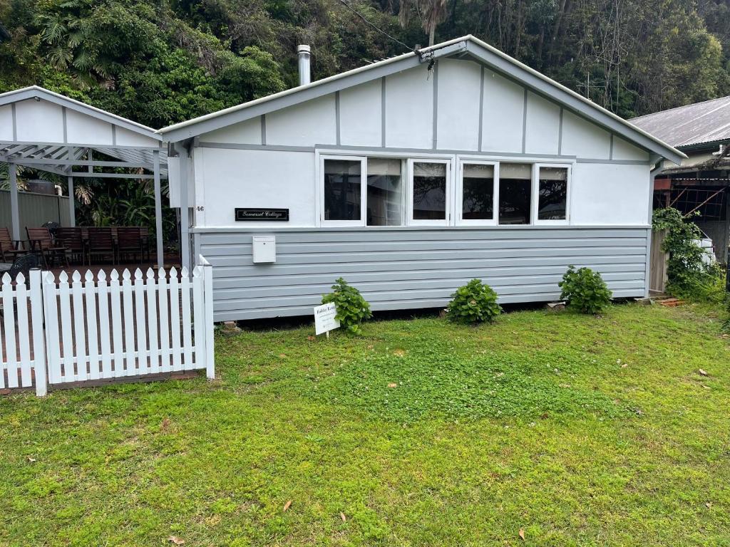 a white house with a white fence in front of it at Patonga Holiday Home in Patonga