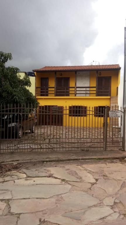 a yellow house with a fence in front of it at Raízes de Afrodite Kitnet in São Thomé das Letras