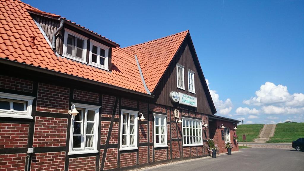 un edificio con techo rojo y ventanas blancas en Hotel Steinhagen en Damnatz