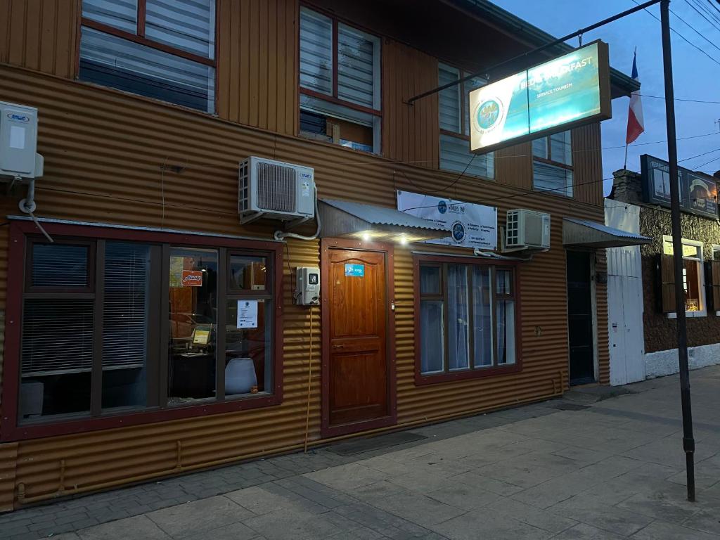 um edifício com um sinal em frente em World's End Hostal em Puerto Natales