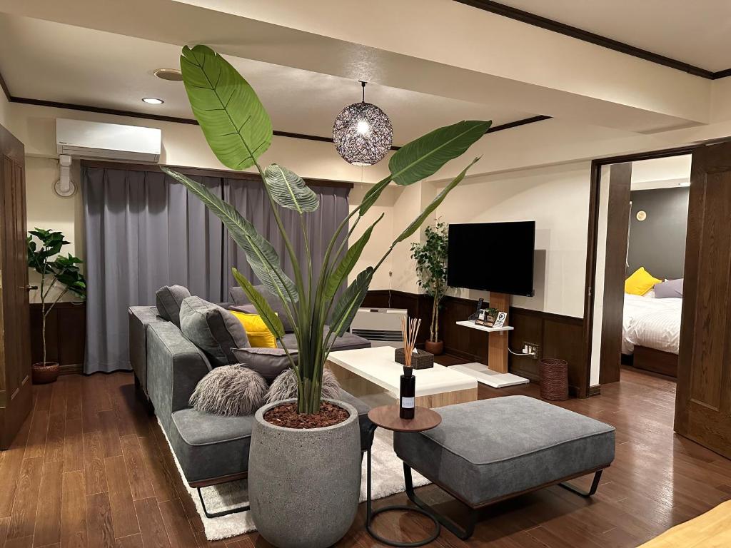 uma sala de estar com um sofá e um vaso de plantas em LIT’S INN Sapporo em Sapporo