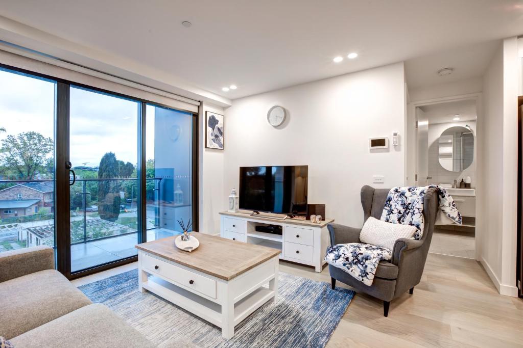sala de estar con TV, sofá y silla en The Hamptons - Lux 2 Bed 2 Bath, Pool - Central Location en Canberra