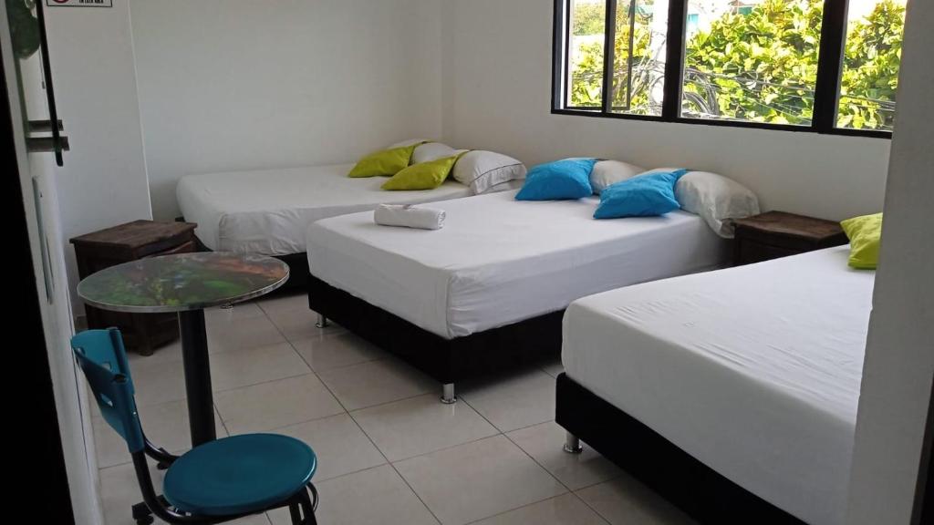 Habitación con 3 camas, mesa y silla en HOTEL ANAPOIMA PLAZA IN, en Anapoima