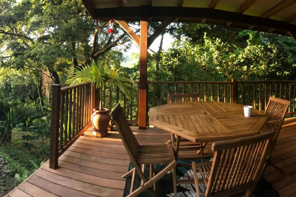 eine Holzterrasse mit einem Holztisch und Stühlen in der Unterkunft Chalet Colibri , Les ANSES d'ARLET 200 m plage in Les Anses-dʼArlets