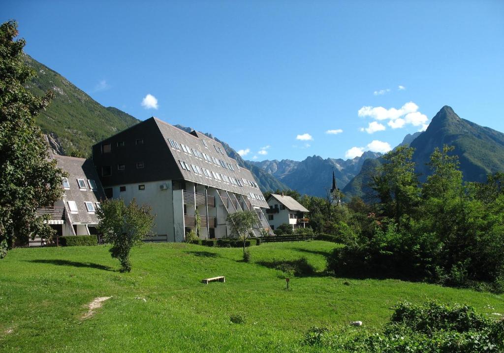 a building in a field with mountains in the background at Apartments Kaninska Vas in Bovec