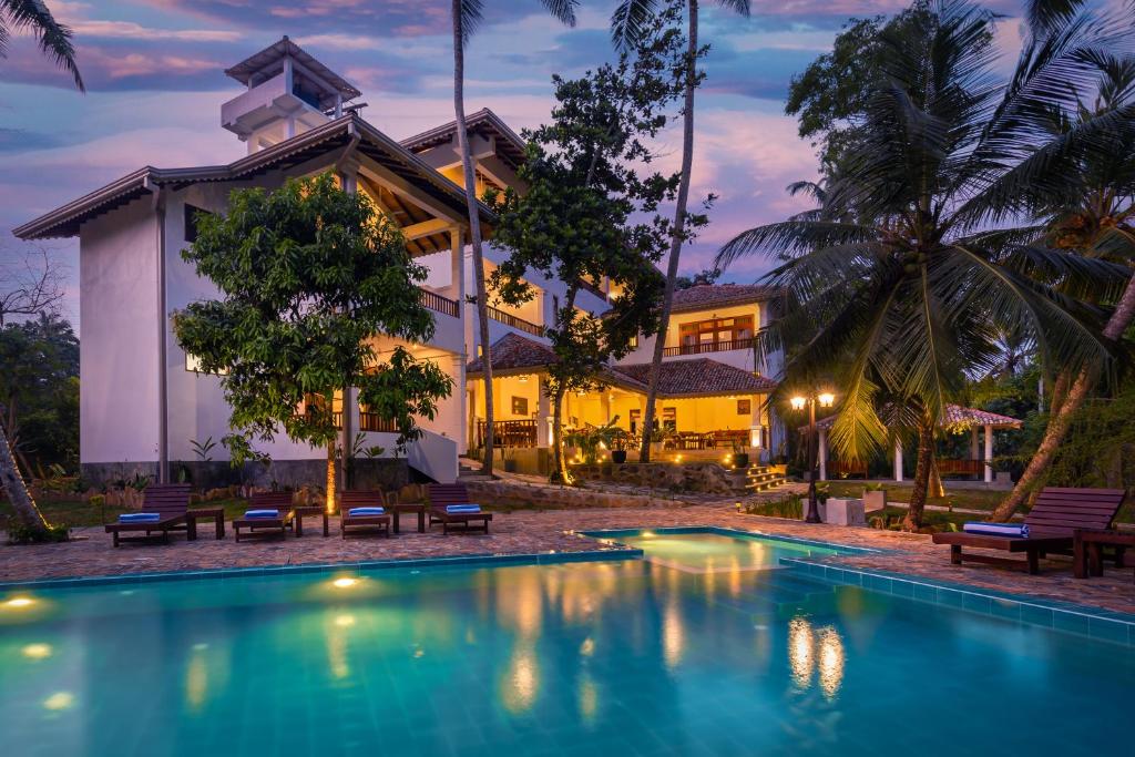 a house with a swimming pool in front of a house at Serenity Boutique - Unawatuna in Unawatuna