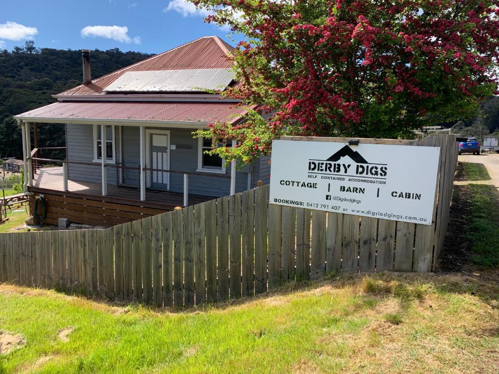 a sign in front of a fence in front of a house at Derby Digs Cottage in Derby