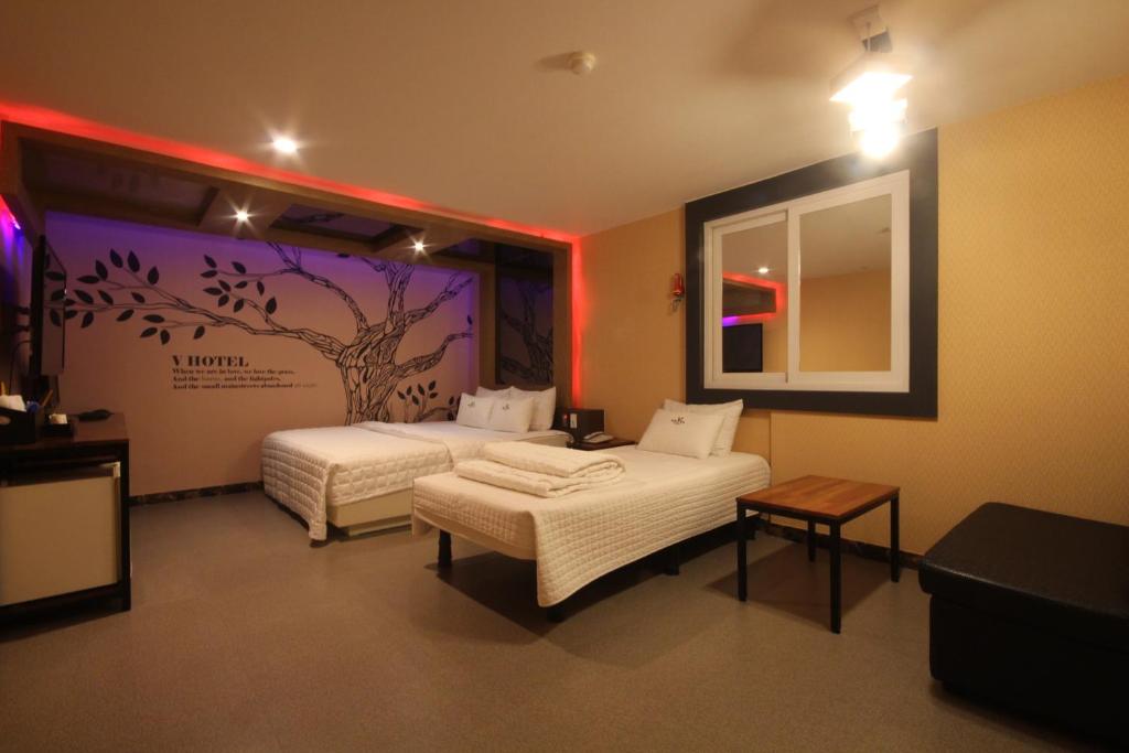 a bedroom with two beds and a tree mural on the wall at v motel in Busan