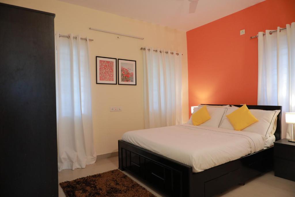 - une chambre avec un lit aux murs orange et des rideaux blancs dans l'établissement Tranquil Staycation - Independent Duplex House, à Hosur