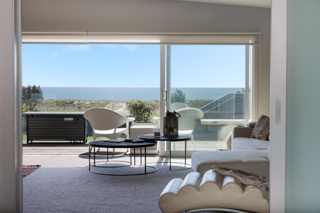 ein Wohnzimmer mit einem Sofa und Stühlen sowie einem großen Fenster in der Unterkunft Luxury Ocean Villa in Papamoa in Papamoa