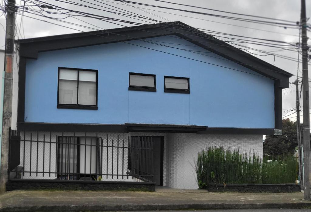 ein blau-weißes Haus mit schwarzen Fenstern in der Unterkunft Casa Azul in Manizales