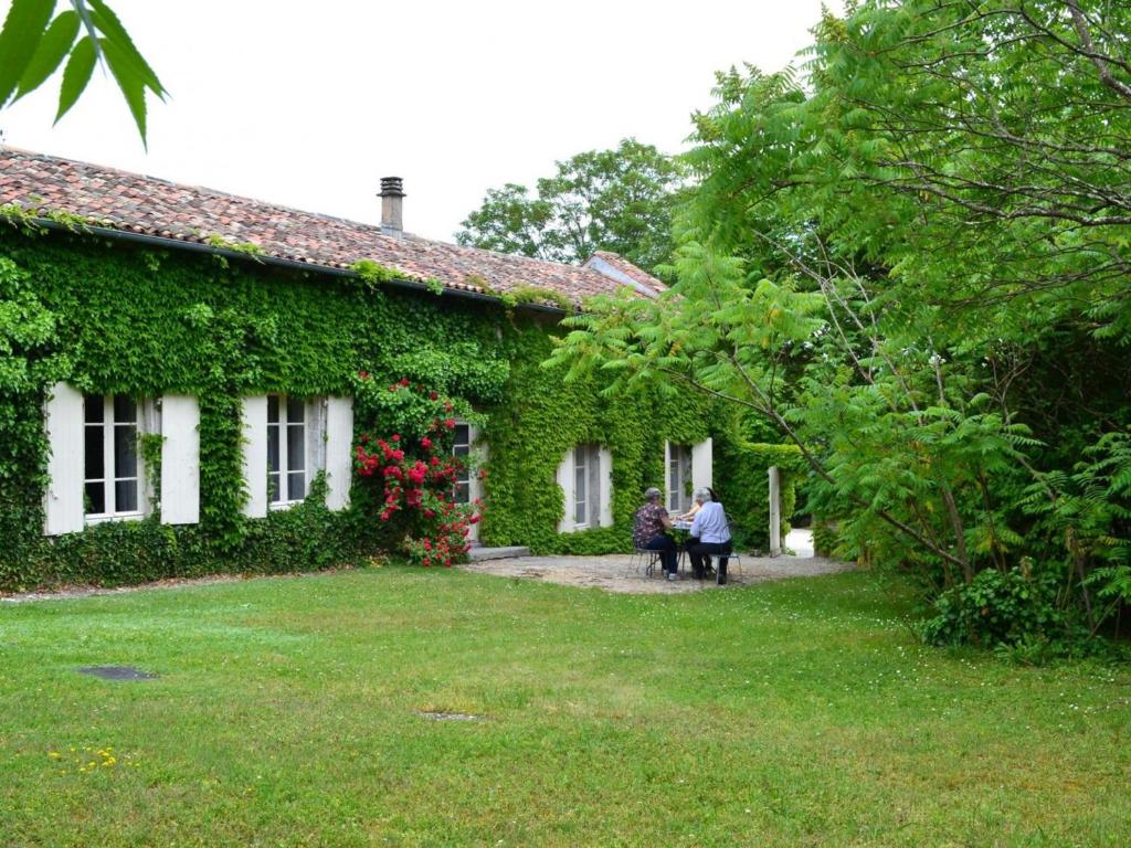 dwie osoby siedzące przed domem porośniętym bluszczem w obiekcie Gîte spacieux avec jardin, piscine, cheminée, et équipements bébé au cœur des vignes du Cognac - FR-1-653-59 w mieście Lignières-Sonneville
