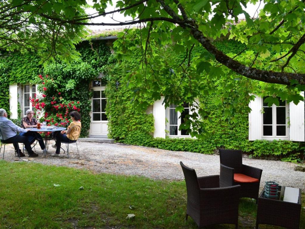 grupa ludzi siedzących przy stole przed domem w obiekcie Gîte spacieux avec jardin, piscine, cheminée, et équipements bébé au cœur des vignes du Cognac - FR-1-653-59 w mieście Lignières-Sonneville