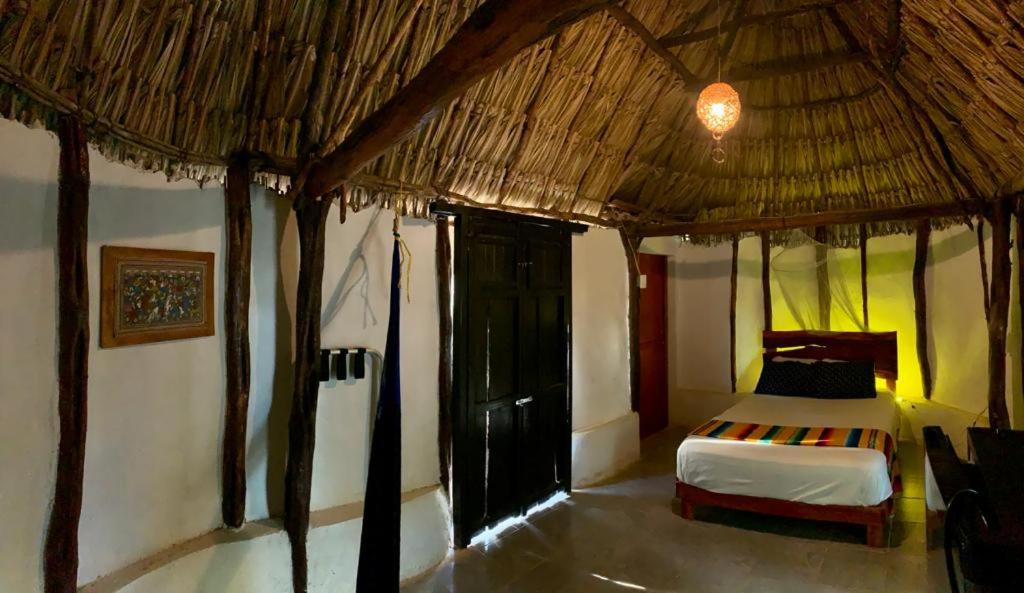 een slaapkamer met een bed in een strohut bij Cabañas Pájaro Azul 