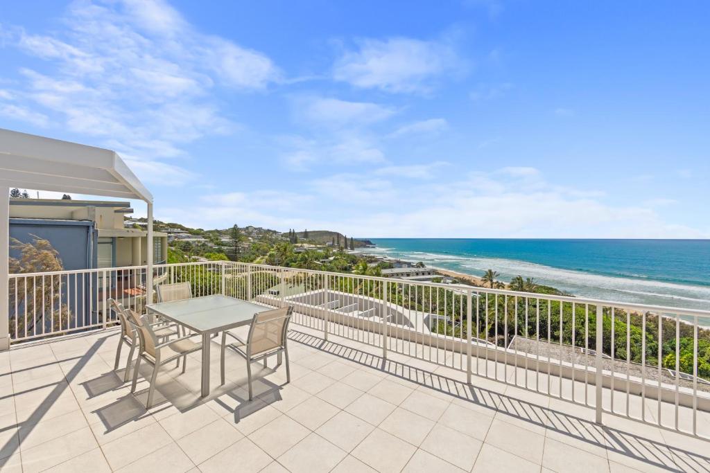 a balcony with a table and chairs and the ocean at La Mer Sunshine Beachfront in Sunshine Beach