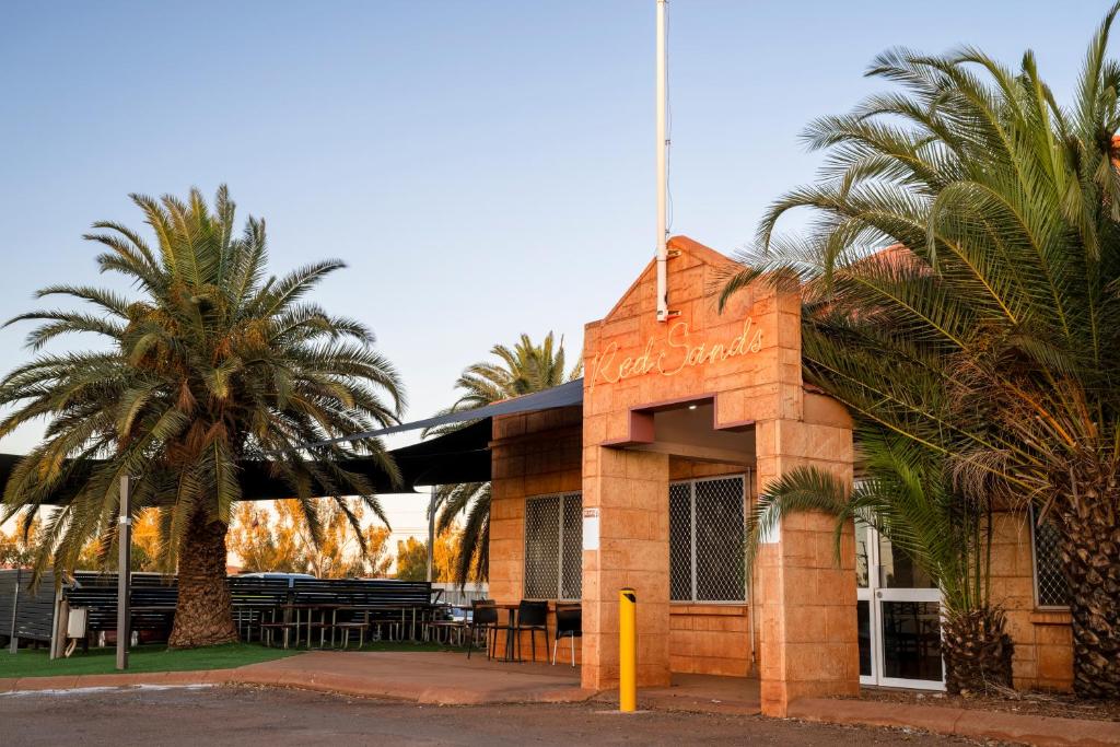 a building with palm trees in front of it at Red Sands Accommodation Newman in Newman