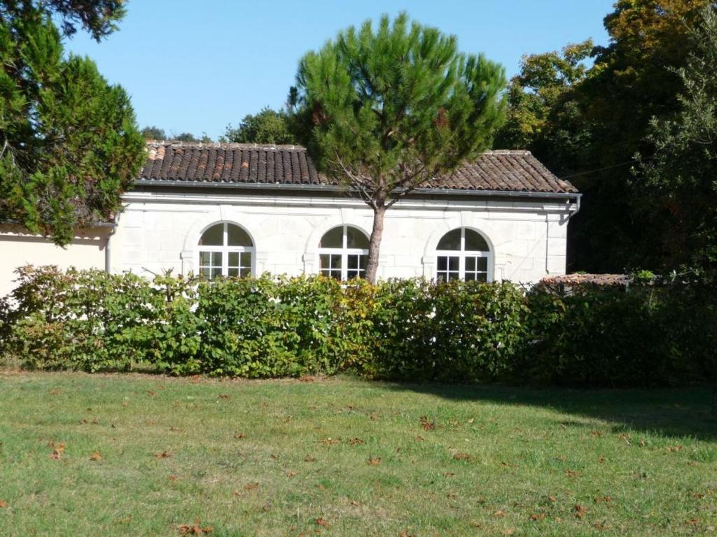 a white house with a tree in front of a yard at Gîte paisible avec jardins privatifs à Cognac, proche des sentiers de randonnée, animaux acceptés - FR-1-653-178 in Cognac